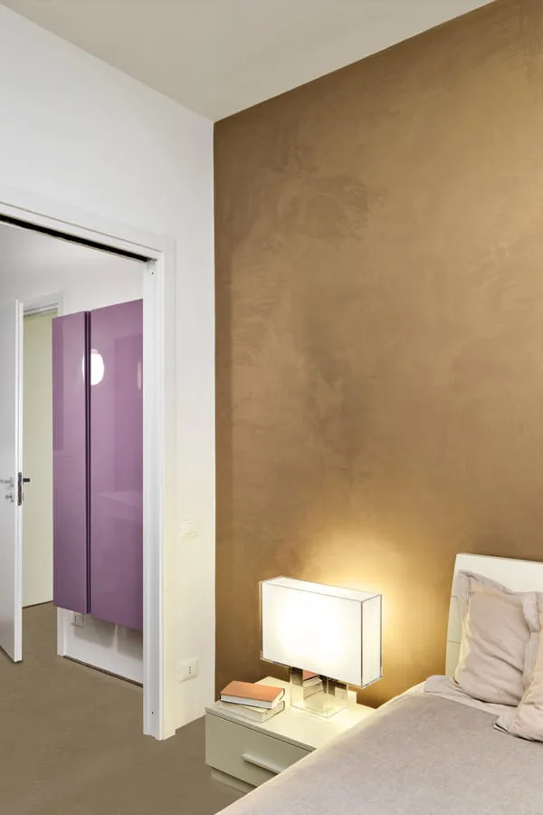 Bedroom decorated with a golden microcement wall